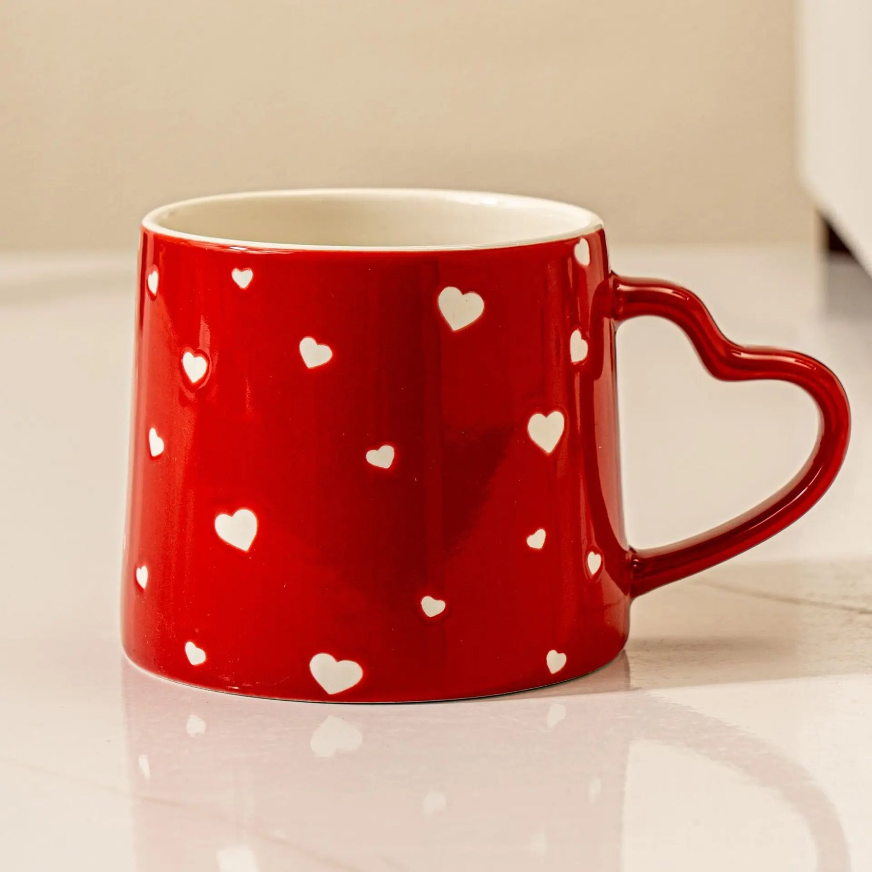 Red mug with white heart patterns on a light surface