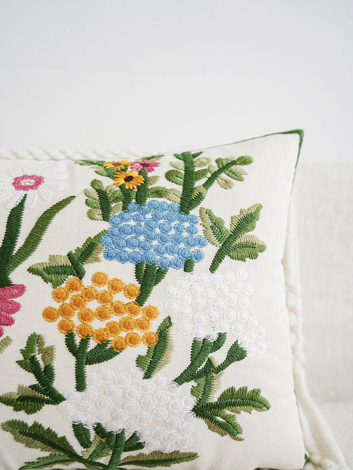 Embroidered floral pillow with colorful flowers on a white background