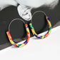 Colorful hoop earrings worn by a person with a black and white background