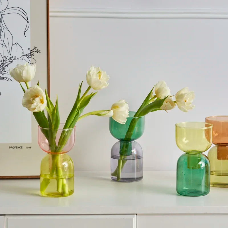 Set of colorful glass vases with tulips on a white surface