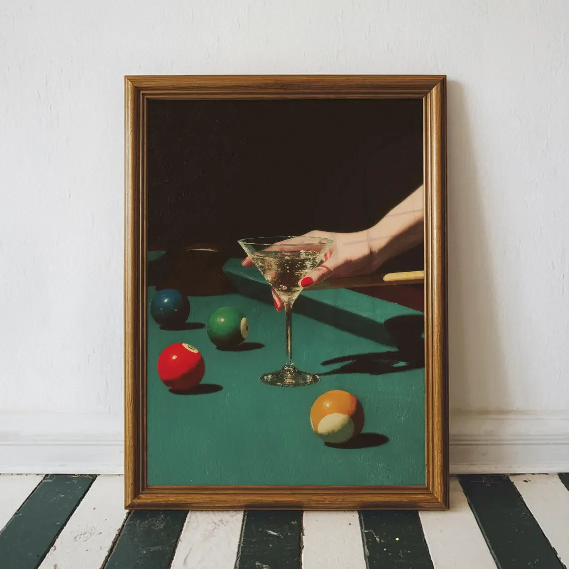 Framed artwork of a hand holding a martini glass on a pool table with colorful balls.