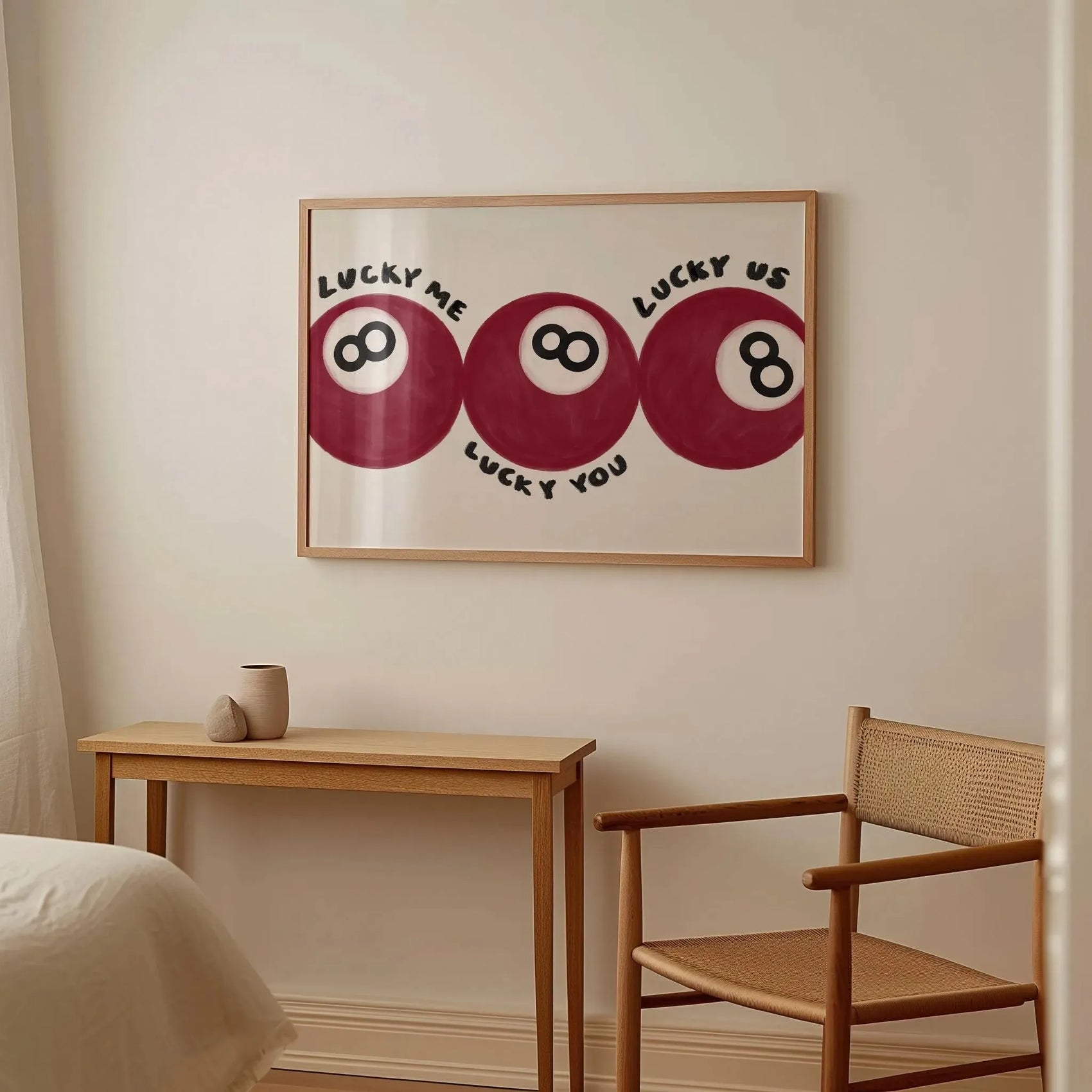 Framed artwork with pool ball design on a wall above a wooden table and chair.
