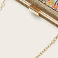 Gold chain attached to a decorative clutch bag on a white background