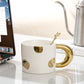 White mug with gold accents on a desk next to a laptop