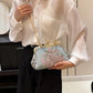 Person holding a floral handbag with a neutral background