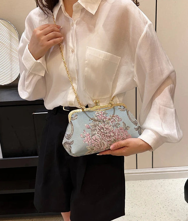 Person holding a floral handbag with a neutral background