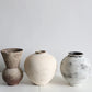 Three ceramic vases with textured surfaces on a white surface and light gray background