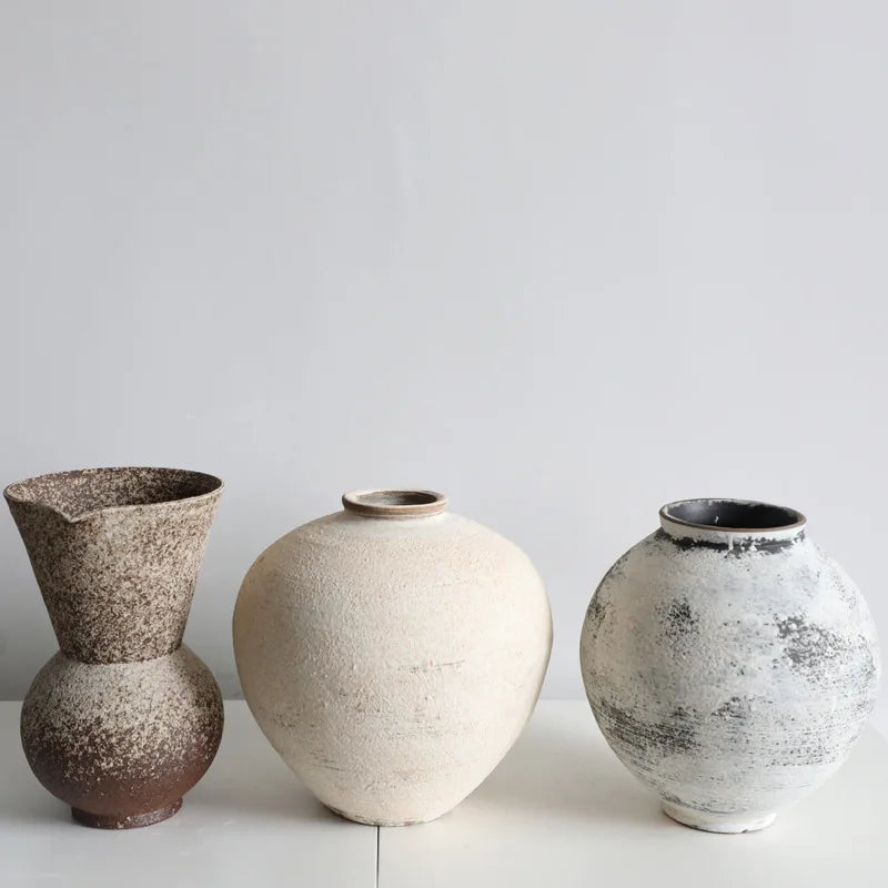 Three ceramic vases with textured surfaces on a white surface and light gray background