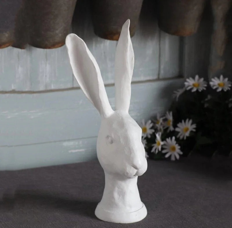 White rabbit sculpture on a dark surface with a blurred background