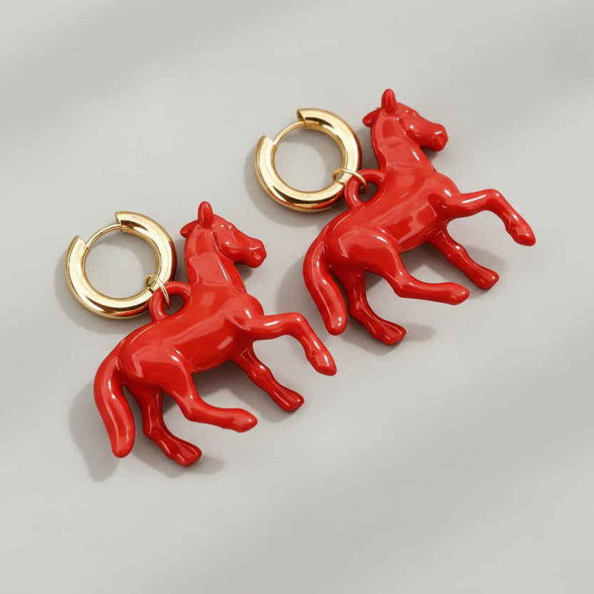 Red horse-shaped earrings on a beige background