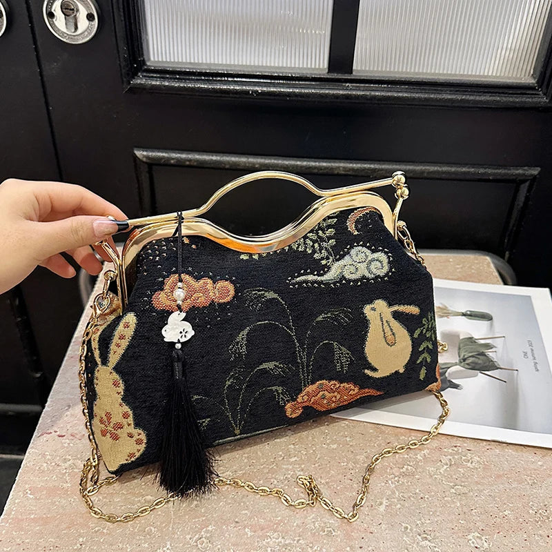 Handbag with intricate design held by a hand on a textured surface.