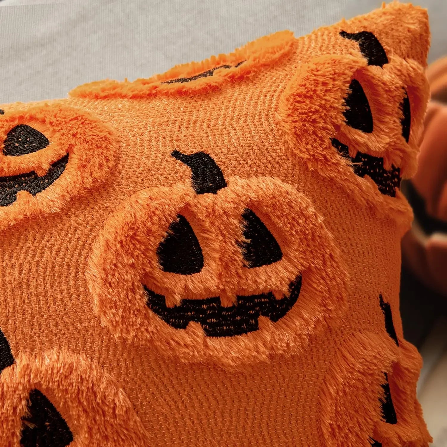 Close-up of orange fabric with black jack-o'-lantern face designs.