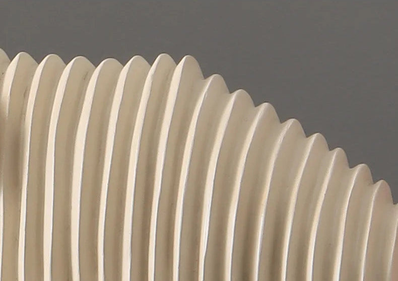 Close-up of a beige corrugated pipe against a dark background
