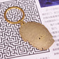 Gold keychain with a face design on a patterned background