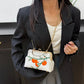 Person wearing a black blazer holding a white handbag with orange design.