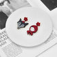 Two small figurines, one black and one red, on a white plate with a magazine underneath.