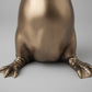 Bronze statue of a dog's head and front paws on a wooden surface