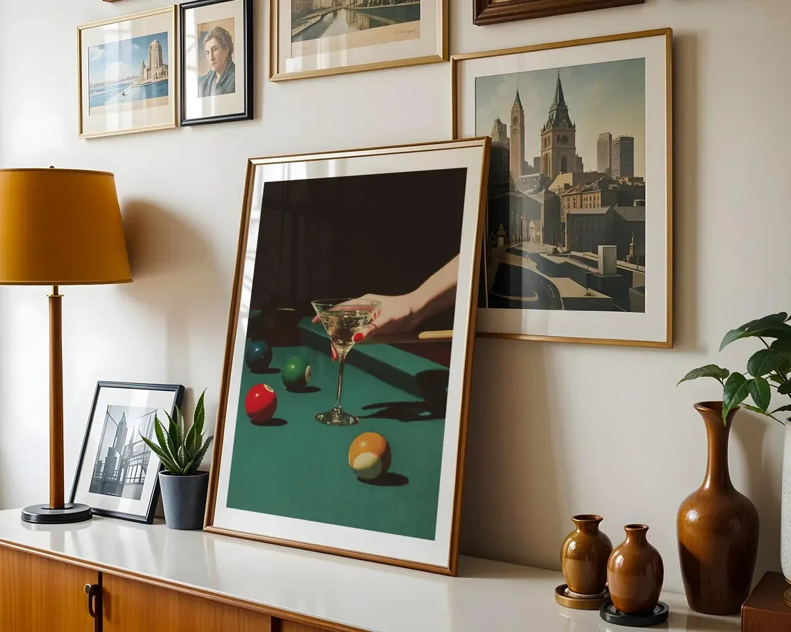 Framed artwork on a wall with decorative items including a lamp, vases, and a plant.