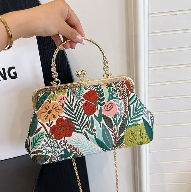 Floral patterned handbag held by a person with a white background