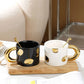Two ceramic mugs with gold handles on a wooden tray.