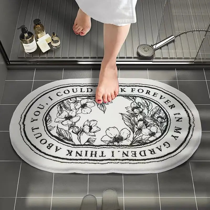 Bathroom scene with a decorative bath mat featuring floral designs and text.