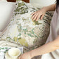 Person arranging a decorative pillow with a world map pattern on a couch.