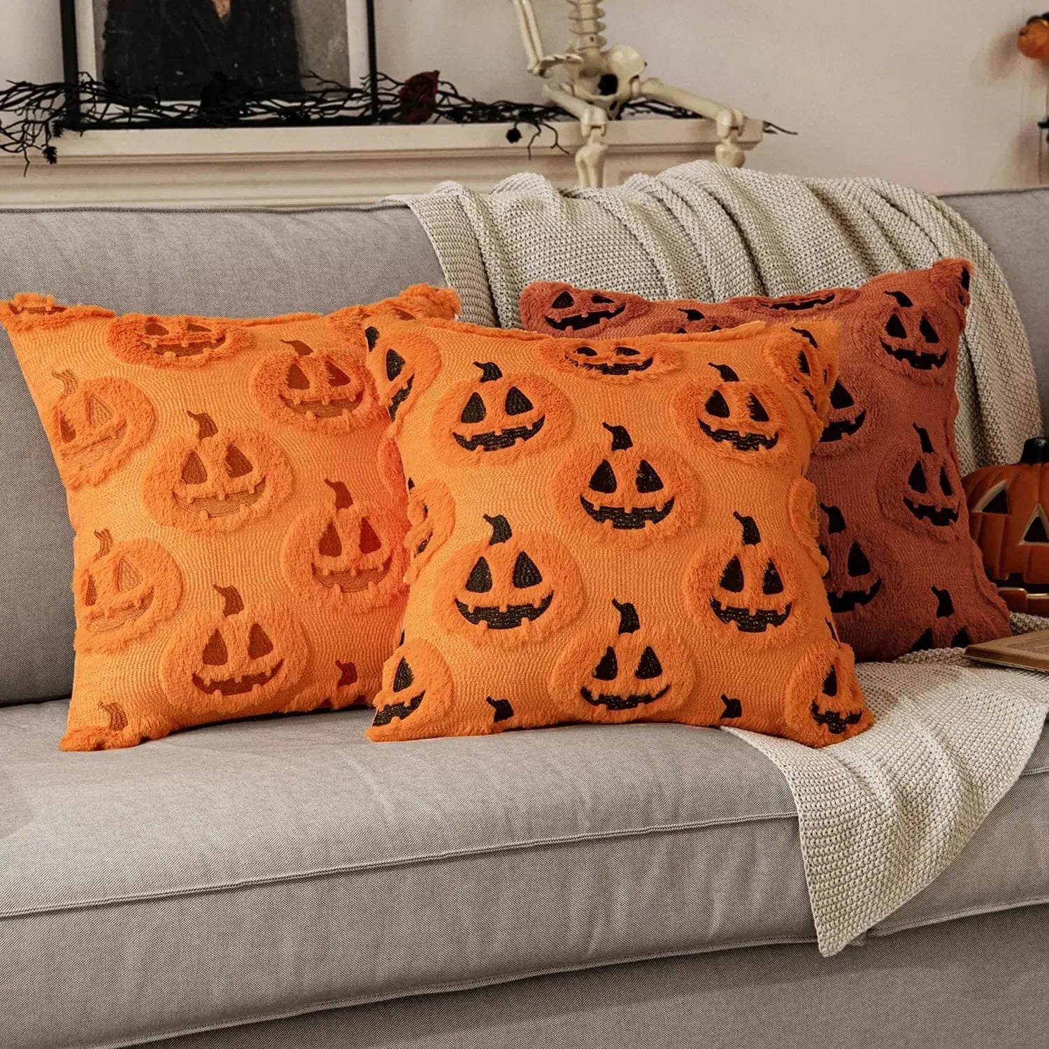 Orange pillows with jack-o'-lantern patterns on a gray couch.