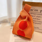 Orange knitted bag with red apple design on a magazine