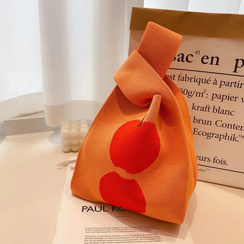 Orange knitted bag with red apple design on a magazine