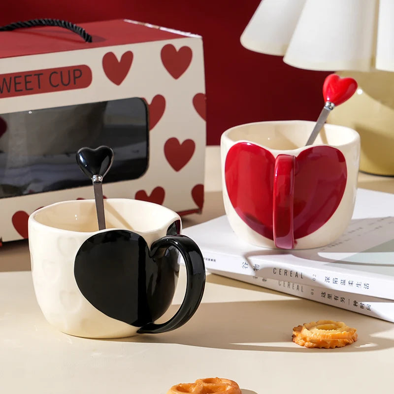 Heart-shaped mugs with matching spoons on a table with a box labeled 'Sweet Cup' in the background.