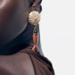 Close-up of a person wearing a fish-shaped earring with a gold top.