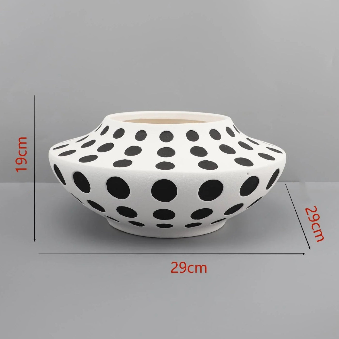White vase with black polka dots on a gray background with measurement labels.