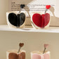 Heart-shaped ceramic cups with spoons on a shelf against a neutral background