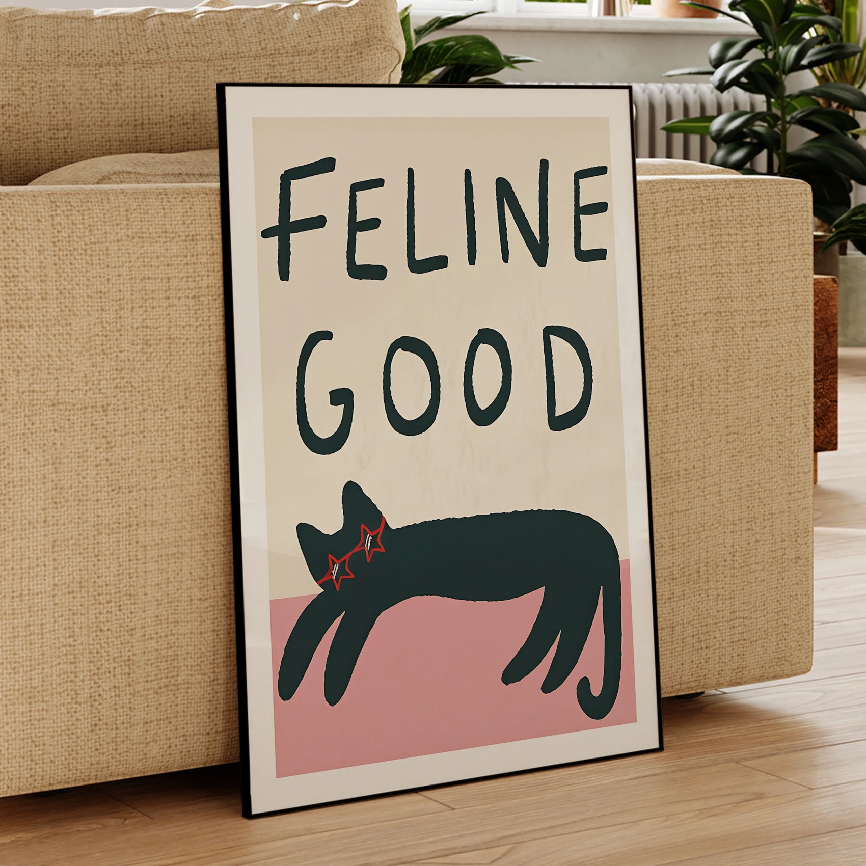 Framed artwork with 'Feline Good' text and a cat illustration in a living room setting.