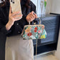 Person holding a floral handbag in front of a television.