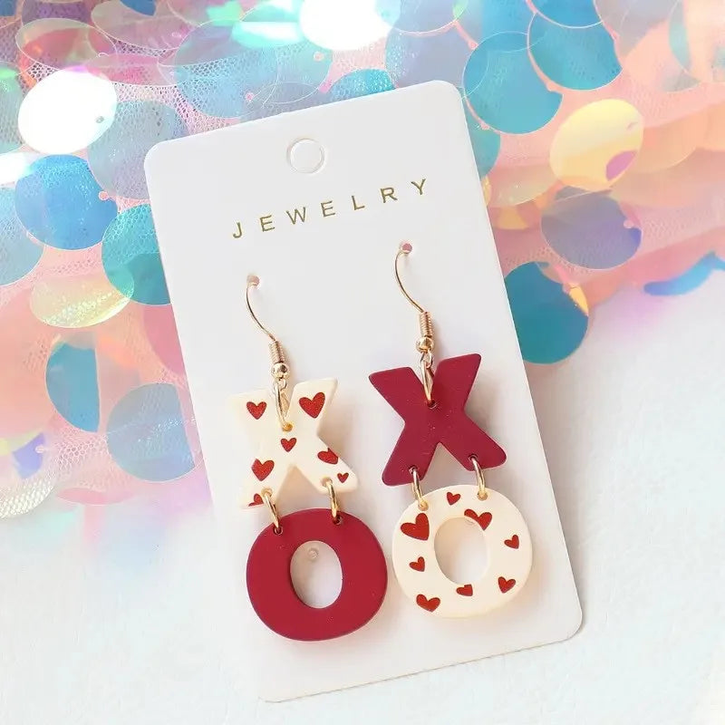 Pair of earrings with 'XO' design on a jewelry card with a colorful confetti background.