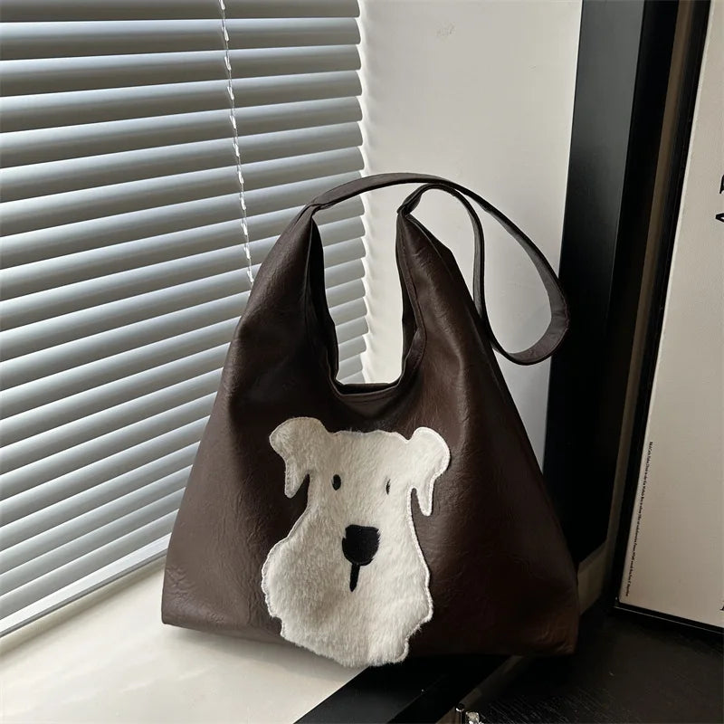 Brown leather bag with a white dog face patch on a surface.