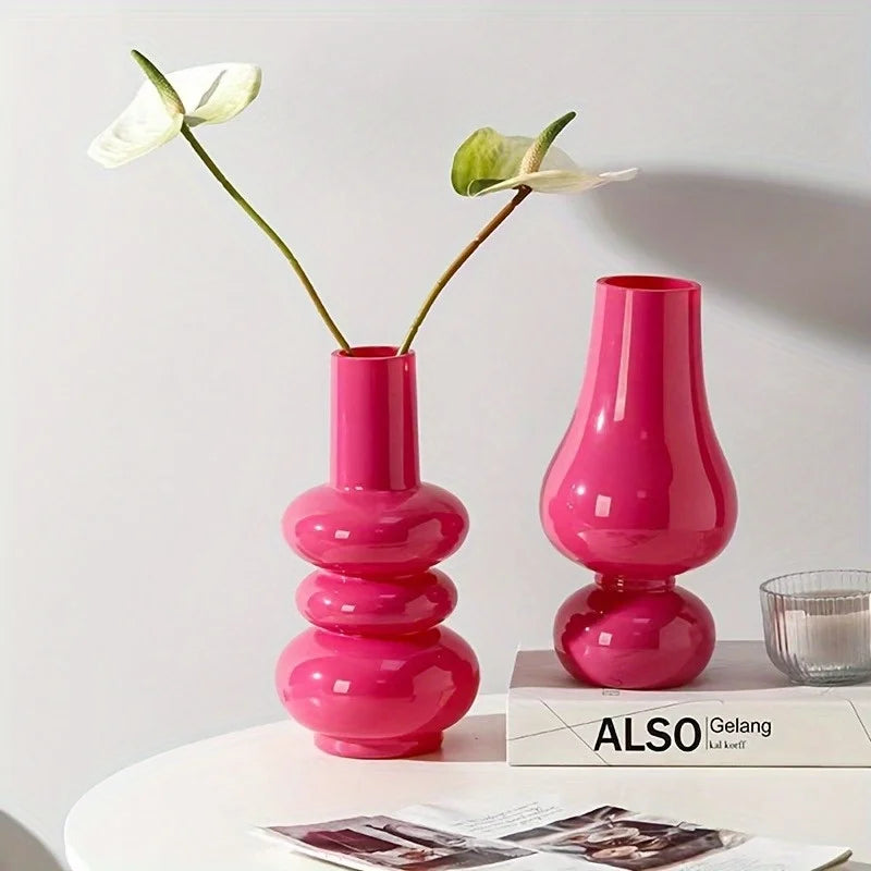 Two pink vases with flowers on a white surface
