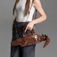 Person holding a brown alligator-shaped handbag against a gray background