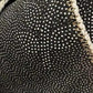 Close-up of textured black fabric with white spots and beige stitching