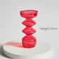 Red glass candle holder on a white surface with a gray background