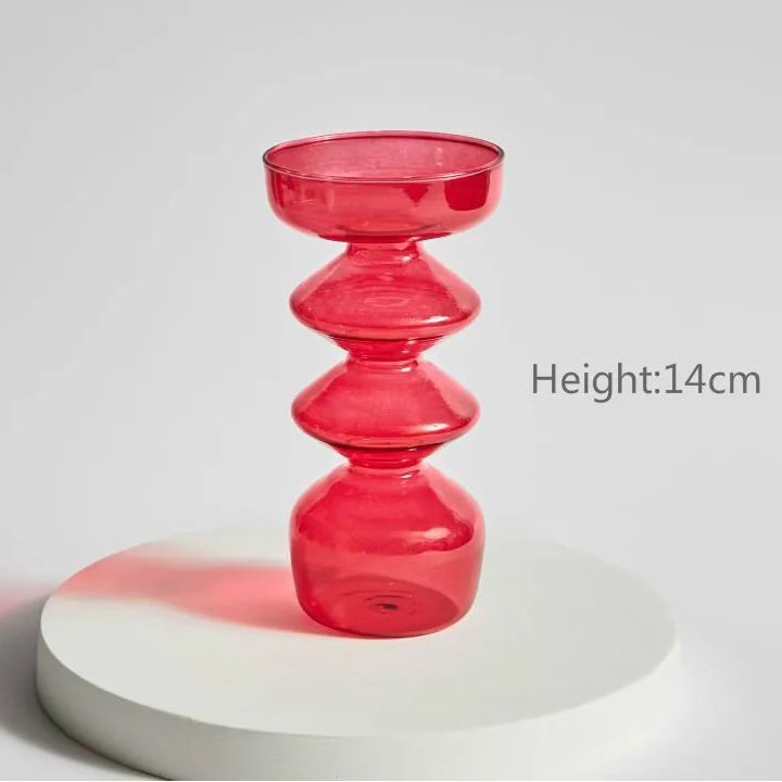 Red glass candle holder on a white surface with a gray background