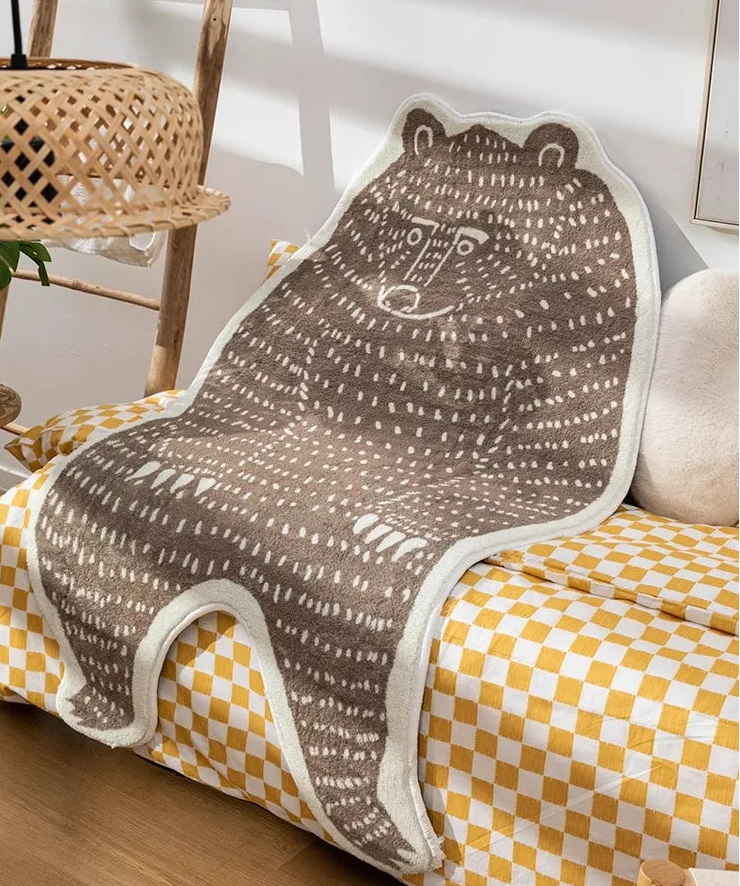 Bear-patterned blanket draped over a yellow and white checkered chair