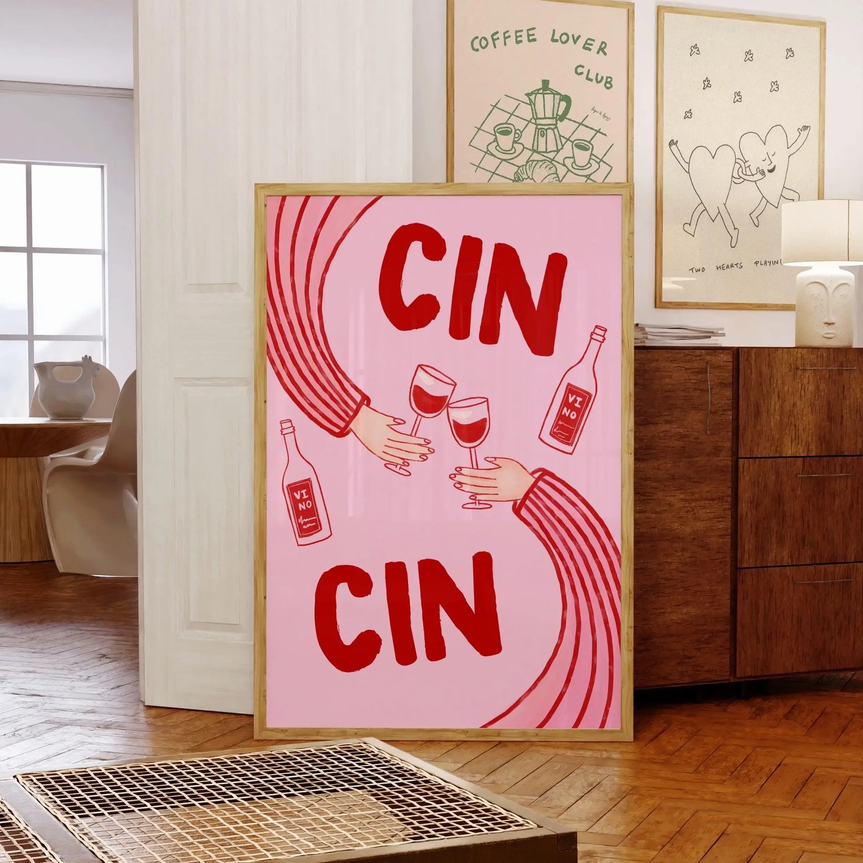 Framed artwork with 'CIN CIN' text and wine graphics in a room setting.