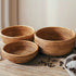 Three woven baskets on a wooden surface with scattered coffee beans.