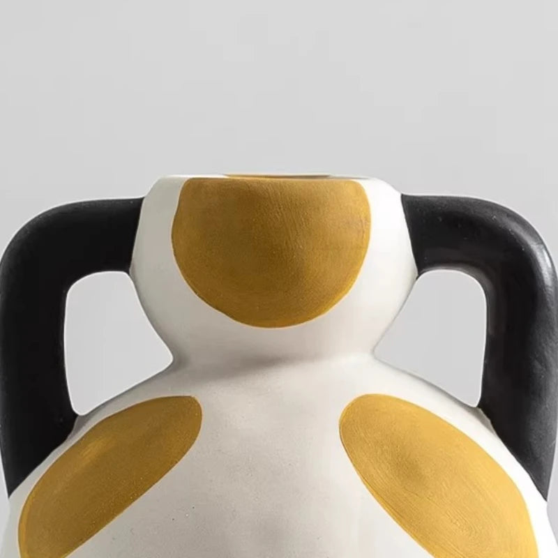 Ceramic vase with black, white, and yellow design on a gray background