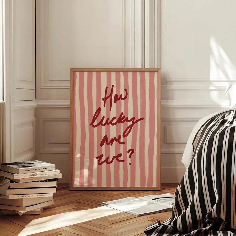 Framed artwork with 'How lucky are we?' text on a striped background in a room setting.
