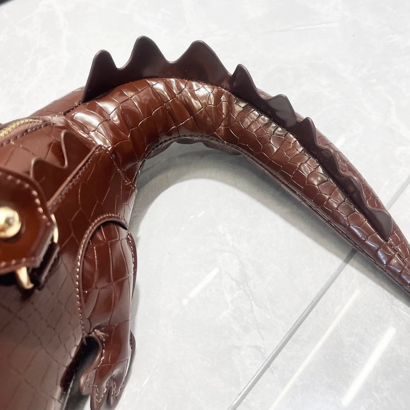 Brown crocodile-patterned handbag on a white background