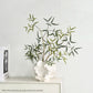 Decorative plant in a white vase on a shelf with a light gray background