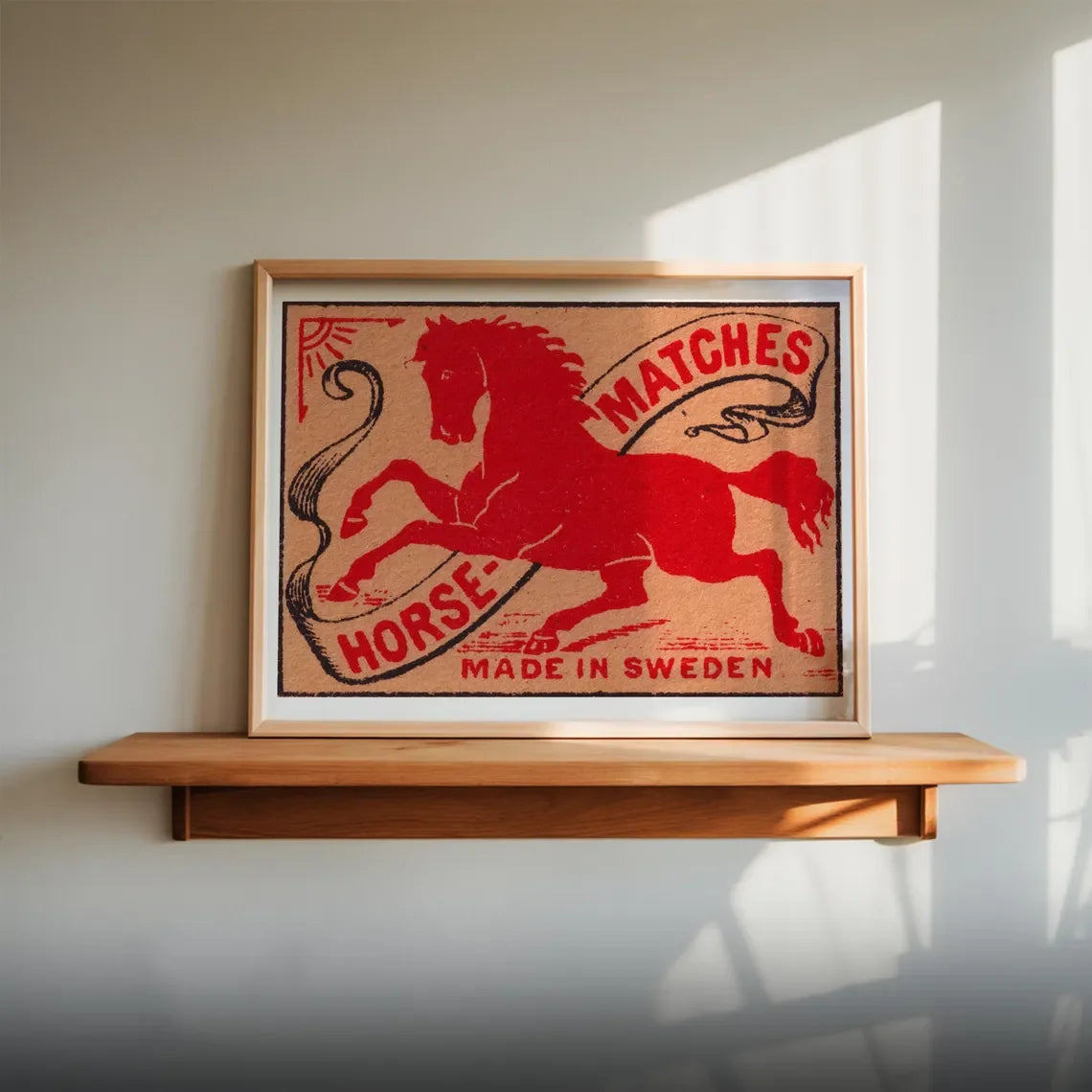 Framed vintage matchbox design with a horse illustration on a wooden shelf.